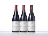 three bottles of red wine are lined up on a table