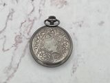 a silver pocket watch sitting on a marble surface