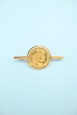 a close up of a gold ring with a coin on it