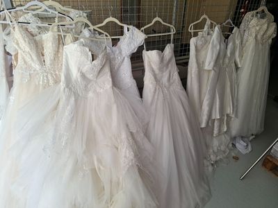 de nombreuses robes de mariée suspendues à un portemanteau dans une pièce