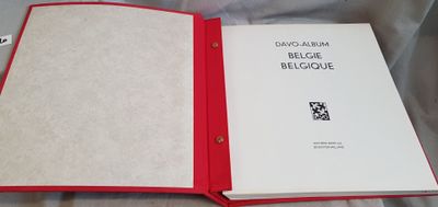 an open book with a red cover sitting on top of a bed