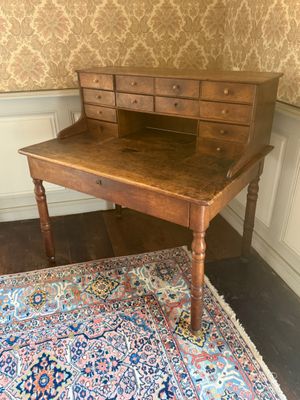 an old wooden desk with drawers and a rug on a wooden floor