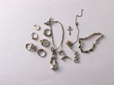 a lot of silver jewelry on a white surface