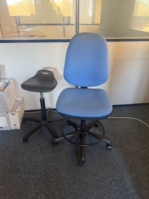 a blue office chair sitting in front of a window
