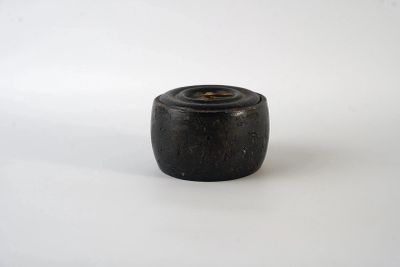 un vieux vase en bois noir posé sur une surface blanche