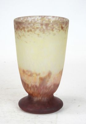a glass vase with a brown base on a white surface