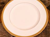 une assiette blanche à bord doré posée sur une table en marbre