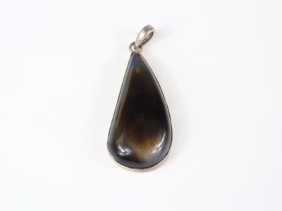 a close up of a tear shaped pendant on a white surface