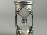 an old silver hourglass with sand in it on a gray surface
