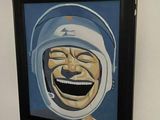 a painting of a smiling man in a helmet hanging on a wall