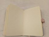 an open notebook on a bed with sheets of paper on it