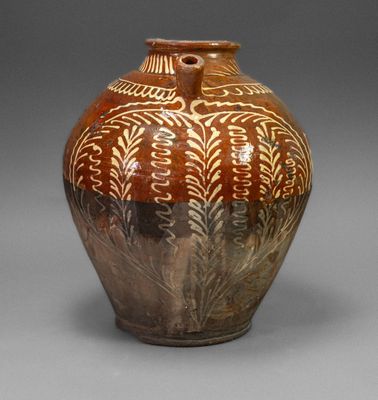 a brown and white vase sitting on a gray surface