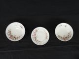 three white bowls with floral designs on them sitting on a black surface