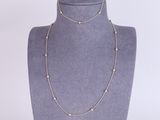 a gold necklace with pearls on a mannequin neck