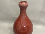 un vase rouge posé sur une surface blanche