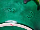 a close up of a green vase with a red flower on it