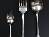 three silver spoons and two silver spoons on a black table