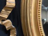 a gold mirror and a gold ribbon hanging on a wall