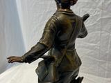 statue en bronze représentant une femme avec un sac et un parapluie, posée sur un socle en marbre