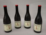 four bottles of wine are lined up on a white surface