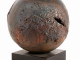 a metal sculpture of a ball on a wooden base