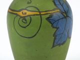 a green vase with a blue flower painted on it