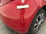 the rear end of a red car with a sticker on it ' s bumper
