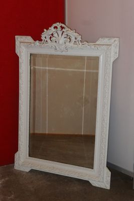 a mirror sitting on the floor in front of a red wall