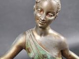bronze statue of a woman holding a flower in her right hand