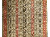 un tapis ancien avec une bordure rouge et des franges