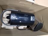 a black coffee maker sitting in a box on the floor