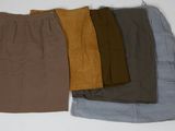 Quatre jupes de couleurs différentes sont alignées sur une surface blanche