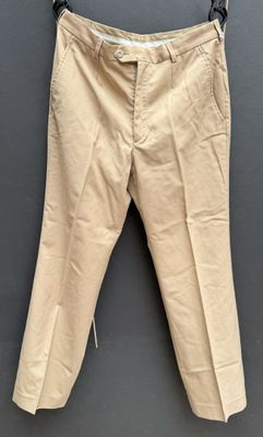 a pair of beige pants hanging on a hanger on a wall