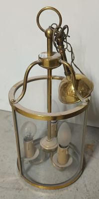 une lanterne en verre et en laiton surmontée d'une ampoule