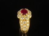 a close up of a gold ring with a red stone