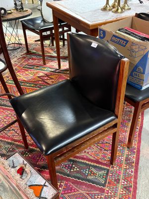 un fauteuil en cuir noir posé sur un tapis au milieu d'une pièce