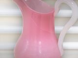 a pink vase with a white handle sitting on a table