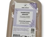 Le flacon de shampoing se trouve dans un récipient en plastique transparent.