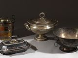 trois plats en argent et une coupe en argent posés sur une table