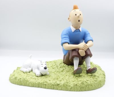 une figurine représentant un homme et un chien sur l'herbe
