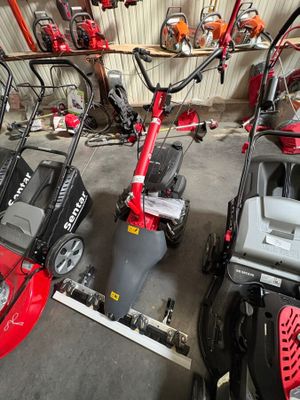 Plusieurs tondeuses à gazon sont alignées en rang dans un garage
