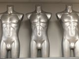 three mannequins sitting on a shelf in a room