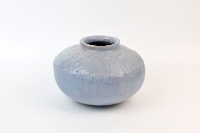 un vase bleu posé sur une surface blanche
