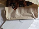 a brown paper bag on a white sheet of paper next to a white envelope