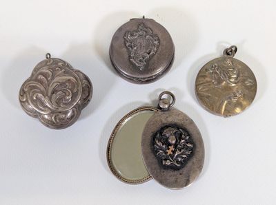 quatre serrures anciennes en argent et un miroir posés sur un support blanc