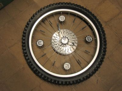a clock on the floor with a bicycle tire on it