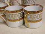 four white and gold coffee cups sitting on top of a table
