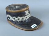 un petit chapeau noir orné d'une croix blanche