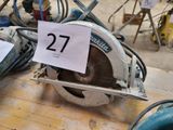 une scie circulaire posée sur une table sur laquelle est inscrit le chiffre 27