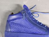 someone is holding a pair of blue shoes on a white surface